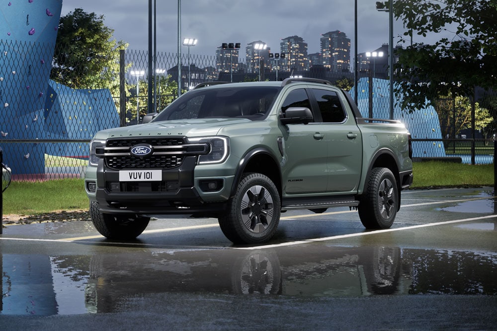 Γκρι Ford Ranger PHEV σταθμευμένο μπροστά από ένα αστικό τοπίο το σούρουπο.