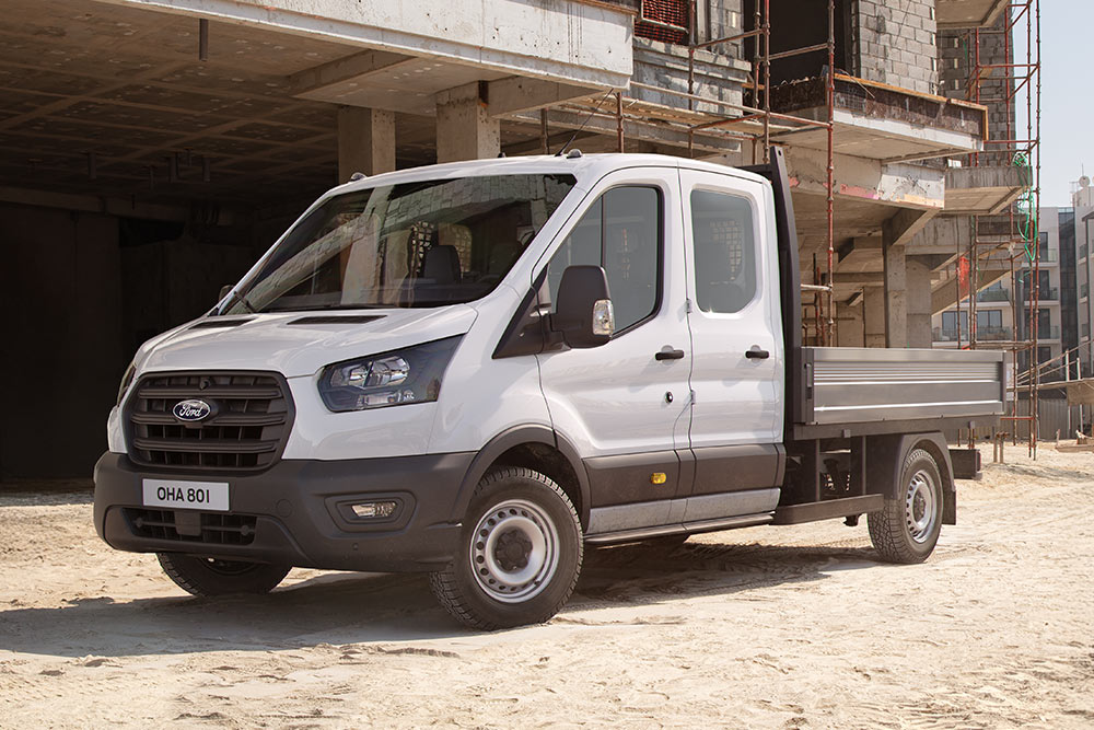 Ένα λευκό Ford Transit Custom με καμπίνα-σασί και καρότσα είναι σταθμευμένο σε εργοτάξιο.