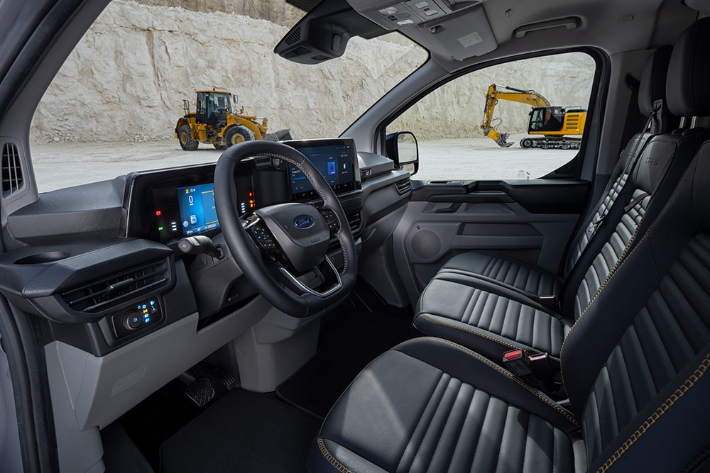 Εσωτερική άποψη ενός Ford Transit Custom van, όπου φαίνεται το ταμπλό, το τιμόνι και τα καθίσματα.