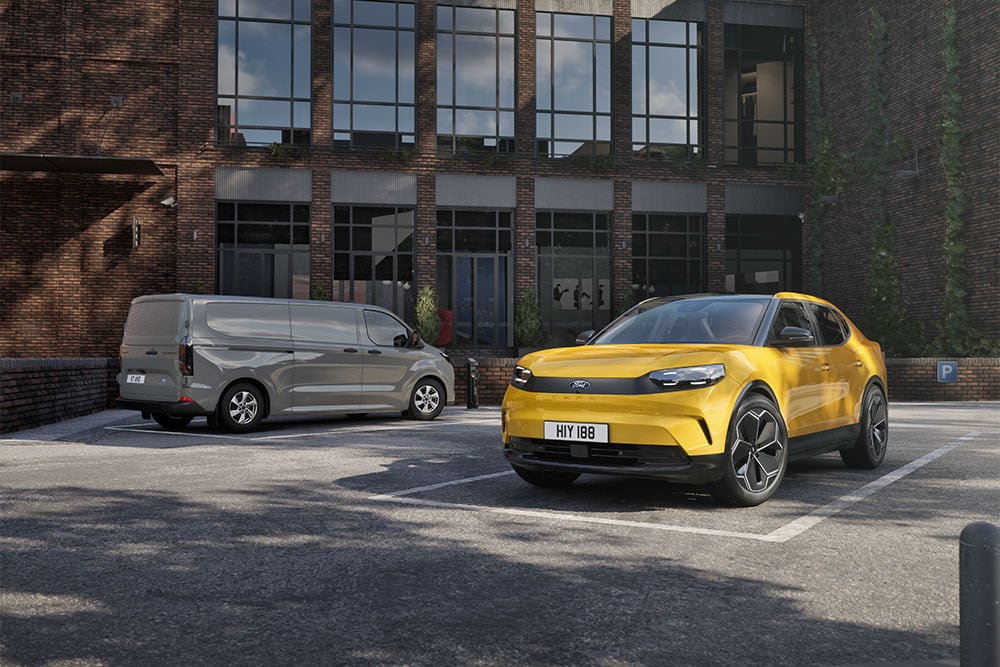  Γκρι van Ford και κίτρινο Capri σταθμευμένα μπροστά από ένα μοντέρνο κτίριο από τούβλα.