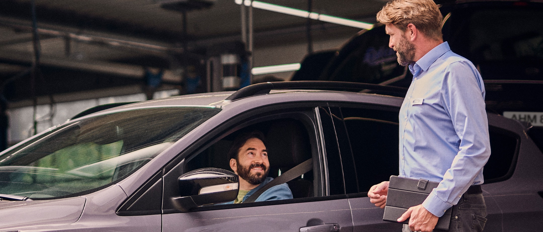 Χαμογελαστός πελάτης μέσα σε γκρι Ford στο Εξουσιοδοτημένο Συνεργείο Ford