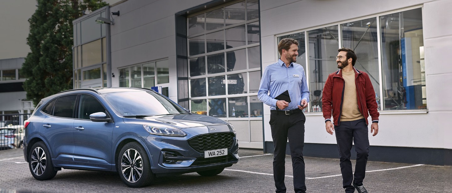 Ford Promotions customer service advisor in front of a Kuga