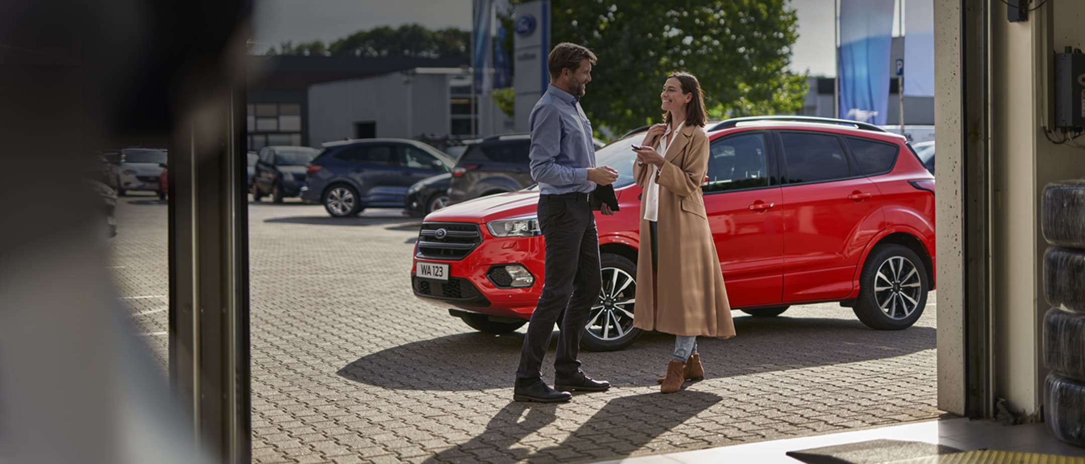 Πελάτης και τεχνικός σύμβουλος μπροστά από κόκκινο αυτοκίνητο Ford σε χώρο συνεργείου