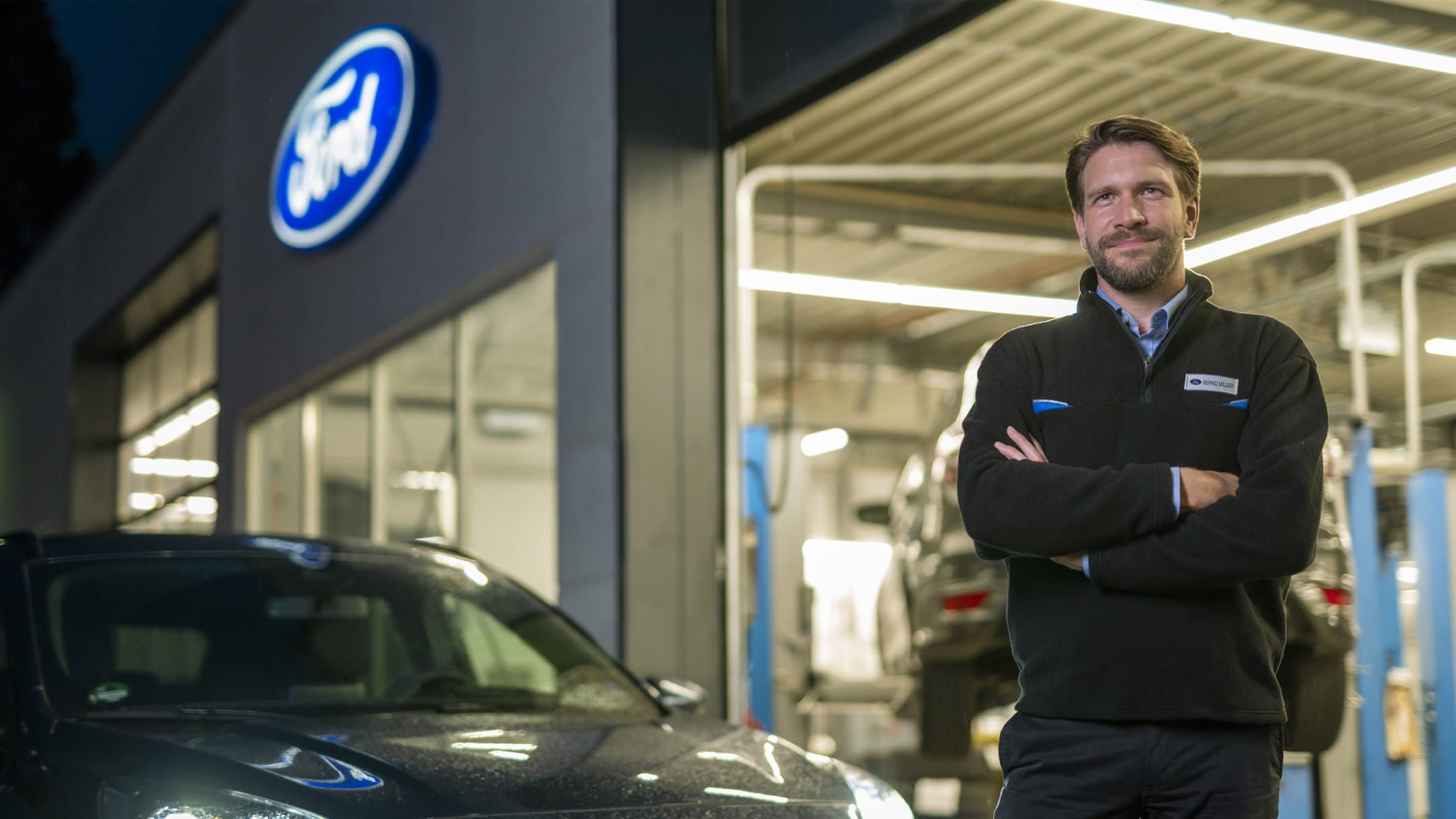 Τεχνικός Ford μπροστά από το συνεργείο και ένα γκρι όχημα