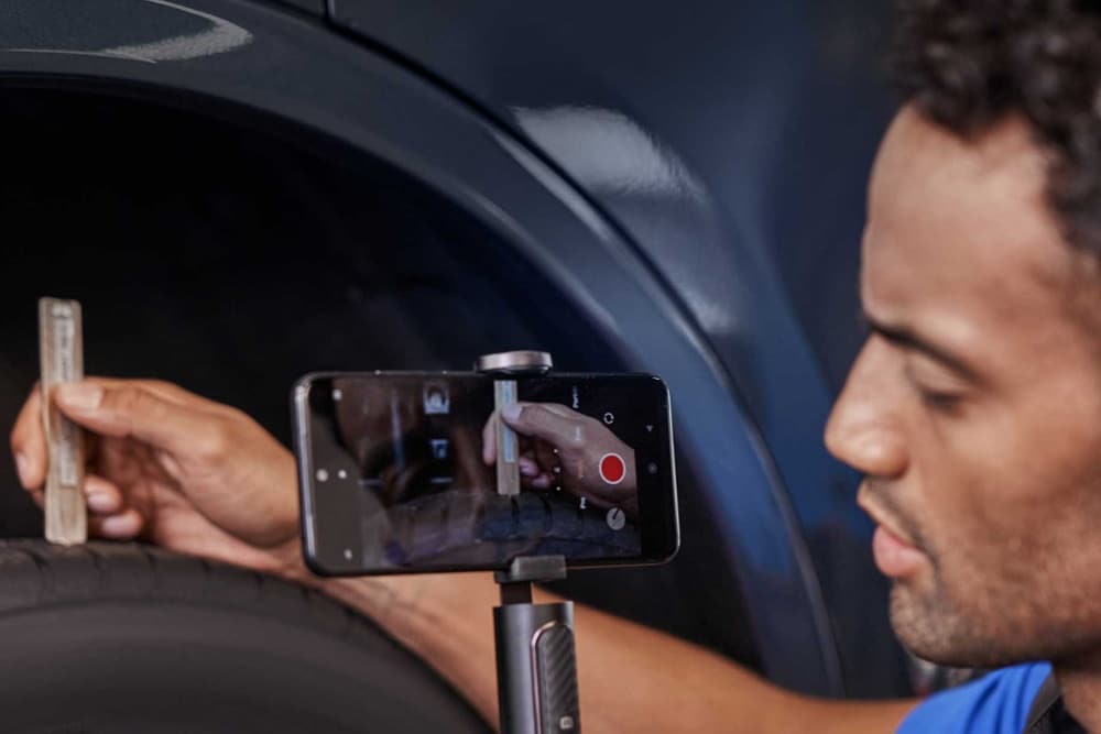 Τεχνικός της Ford χρησιμοποιεί smartphone για να καταγράψει σε βίντεο τον έλεγχο ενός ελαστικού οχήματος.